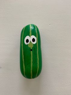 a watermelon painted like a face with googly eyes hanging on a wall