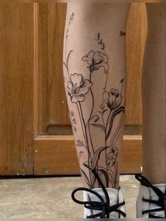 a woman's legs with flowers on them and black laces around the ankles