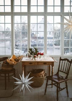 a dining room table and chairs in front of large windows with snowflakes hanging from them