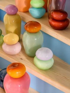 there are many different colored vases on the shelves