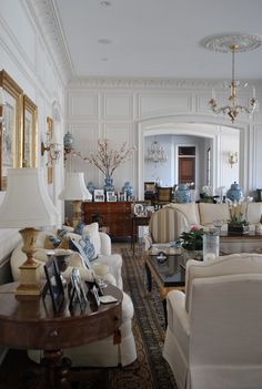 a living room filled with white furniture and blue vases on top of each other