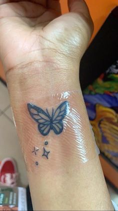 a hand with a butterfly tattoo on it's left wrist and stars around the wrist