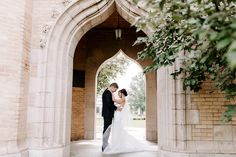 a bride and groom standing under an archway