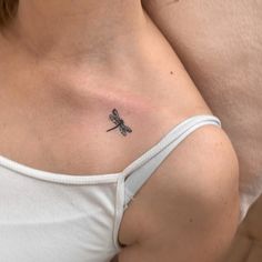 a woman's stomach with a small tattoo of a dragonfly on her left side