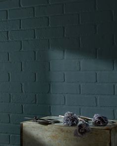 a wooden box with flowers on it against a brick wall