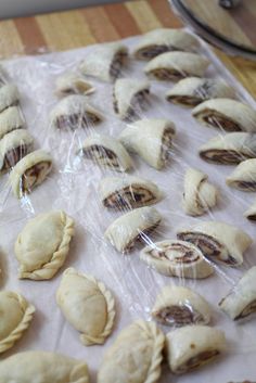 several pastries are wrapped in plastic on a wooden counter top, ready to be baked