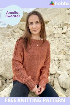 a woman sitting on rocks wearing an orange sweater