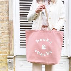 The perfect everyday tote for life's most important things, books and snacks! Our large canvas bags are the perfect spacious totes for your daily essentials and much more. Ideal for school, family days out, beach trips, you name it! A perfect gift for students, teachers, mums, and book & snack lovers everywhere. This hand illustrated 'Books & Snacks' design has been printed in off-white on sturdy blush pink canvas. Suitable for carrying by hand or over the shoulder. Lovingly designed and made in the UK. Made in the UK 15oz thick pink canvas Deep flat base Mid-length handles 480mm by 390mm by 120mm (19 by 15½ by 4¾ inches) Gift Bag Design Ideas, Tote Bag Photography Ideas, Snacks Design, Pink Canvas Tote Bag, Teacher Essentials, Midwife Gift, Canvas Bag Design, Gift For Students, Pink Books