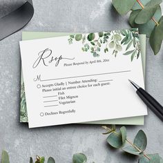 a wedding rsp card with greenery on it and a pen next to it