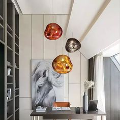 three lights hanging from the ceiling above a desk in a room with bookshelves