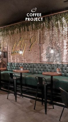 the interior of a coffee shop with green booths and black chairs, hanging plants on the wall