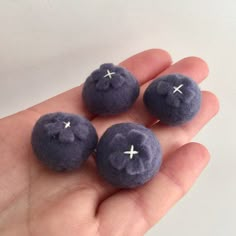 three small blue balls with white crosses on them sitting in someone's left hand