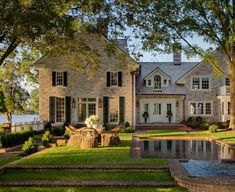 a large house with a pool in front of it and trees around the pond area