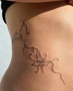 a woman's stomach with an intricate tattoo design on the bottom part of her belly