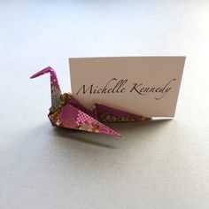 an origami bird holding a name card