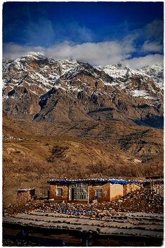 the mountains are covered in snow and there is an old building with broken down windows