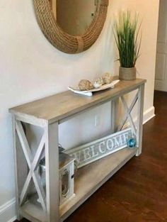 a wooden table with a mirror on the wall above it and a potted plant next to it