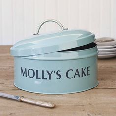 there is a blue cake tin with the words helen's cake on it next to some plates