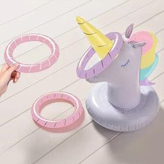 a person holding an inflatable unicorn toy next to other toys on a table