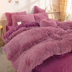 a bed with purple comforters and pillows in a room