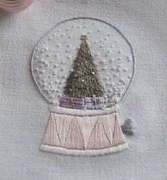 a snow globe with a christmas tree in it on top of a table next to some yarn