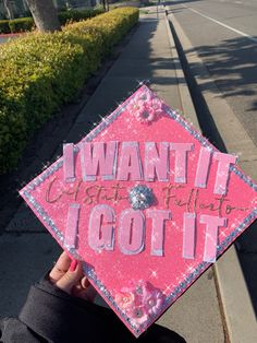 someone holding up a pink graduation cap that says i want it got it on the front