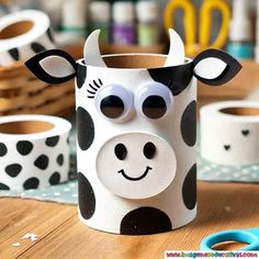 a cow made out of toilet paper sitting on top of a table next to scissors