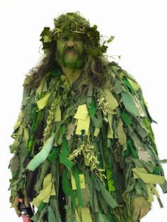 a man dressed in green leaves holding a wine bottle and wearing a costume made out of plants