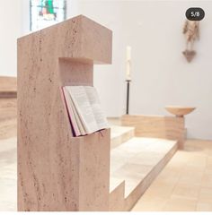 an open book sitting on top of a wooden shelf in a room with white walls