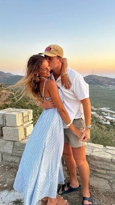 a man and woman hugging each other on top of a hill