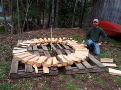 a man kneeling down next to a pile of wood