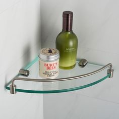 a glass shelf with a bottle and candle on it next to a wall mounted towel rack