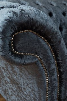 an upholstered grey velvet chair with gold beading