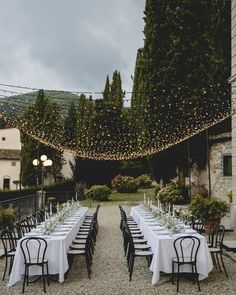 an outdoor dining area with long tables and white tablecloths set up for dinner