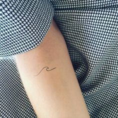 a woman's arm with a small wave tattoo on it