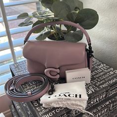 a pink purse sitting on top of a table next to a plant