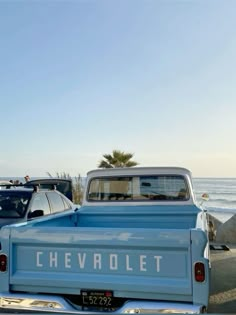 an old blue chevrolet truck parked on the beach