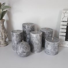 marbled candles sit on a mantle next to a potted plant