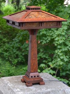 a wooden lamp on top of a rock in front of some trees and bushes,