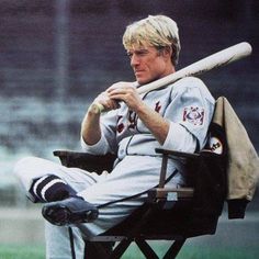 a man sitting in a chair holding a baseball bat