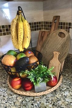 a basket filled with fruit sitting on top of a kitchen counter next to a cutting board