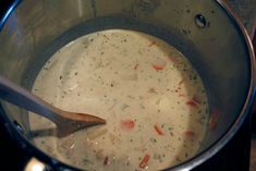 a pot filled with soup on top of a stove next to a wooden spatula