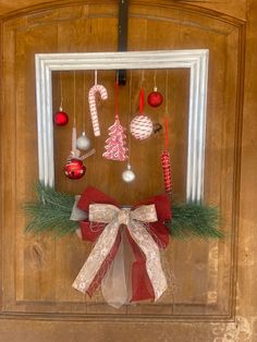 a christmas wreath with ornaments hanging from it's side and on the front door