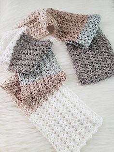 two crocheted scarves laying on top of a white furnishing area