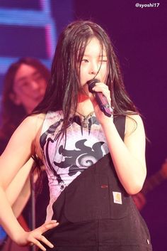 a woman with long hair holding a microphone in her hand and singing into the microphone