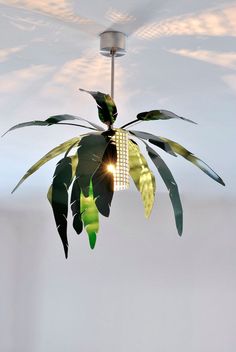 a light that is hanging from the ceiling with some plants on it and leaves growing out of it