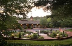 a house with a fountain surrounded by greenery and lit candles in the front yard