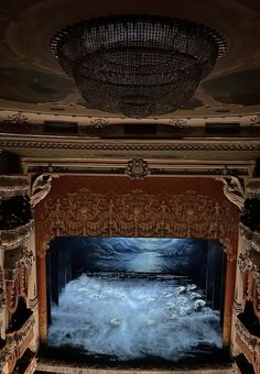 an empty theater with the stage covered in fog and water flowing down it's walls