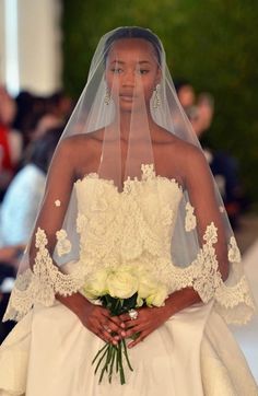 a woman in a wedding dress with a veil on her head and flowers in her hand