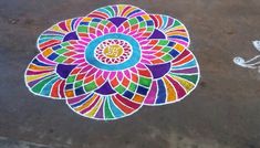 a colorful flower is drawn on the ground next to a white object with an intricate design